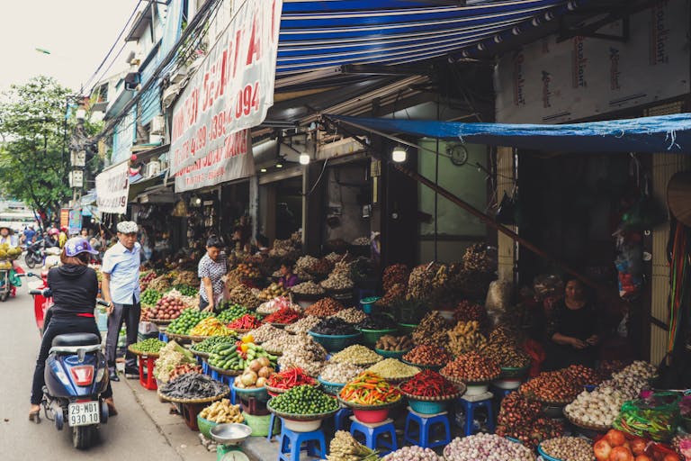 Bustling outdoor street market in Hanoi featuring colorful produce and local vendors.