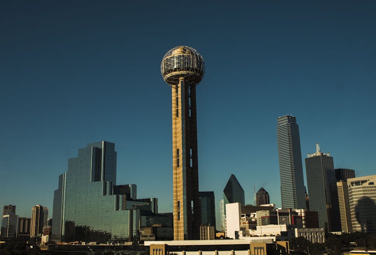 Iconic Dallas skyline with Reunion Tower under a clear blue sky.