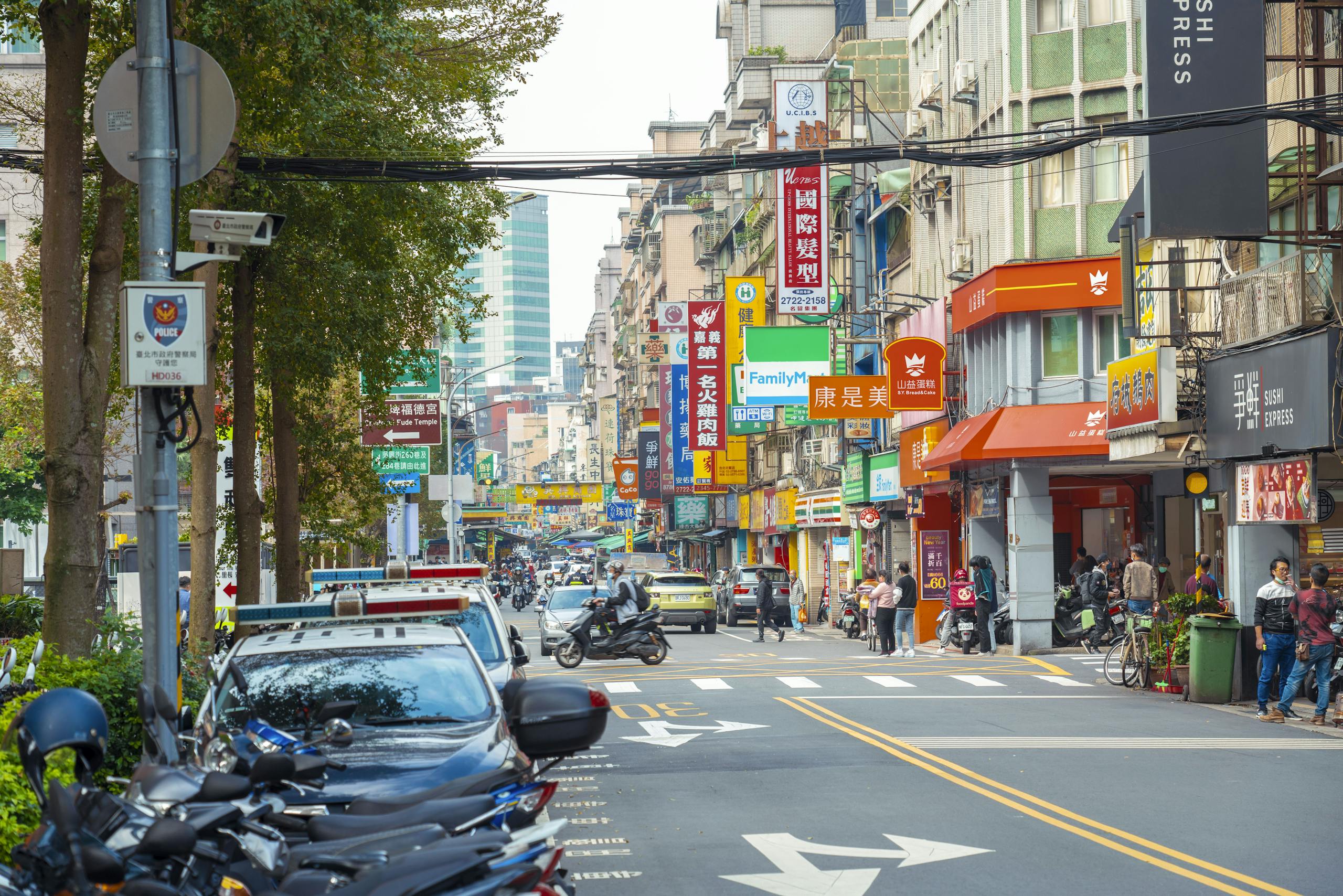 Lively city street with shops and pedestrians, showcasing bustling urban life.